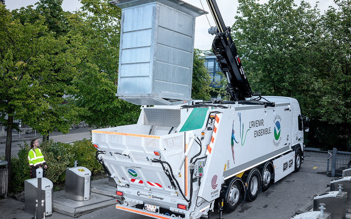 Elektrolastwagen im Einsatz beim Heben einer Mulde.